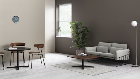 Zwei Everywhere Tables in einem entspannten Sitzbereich, mit Leeway Stühlen aus Holz und einem grauen Wireframe Sofa.