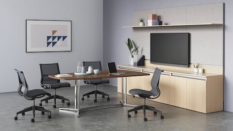 Ein ovaler Everywhere Table für Videokonferenzen aus dunklem Holz in einer Videokonferenz-Umgebung, umgeben von vier Setu Stühlen.