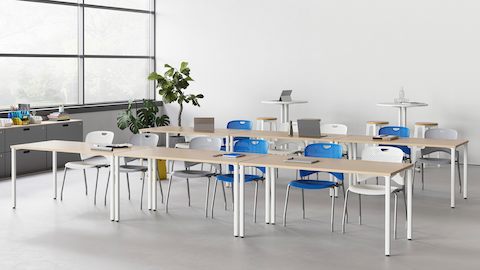 Eine Lernumgebung mit zwei Reihen von Everywhere Tables und Caper Stapelstühlen in verschiedenen Farben.