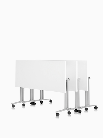 Three white Everywhere Tables, nestled together in the folded position.