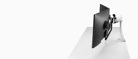 White dual Flo X monitor arm set up with 32'' screens, viewed from the side.