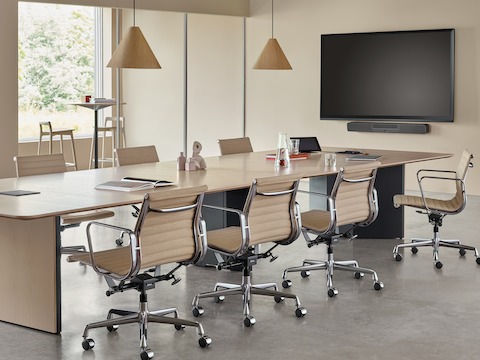 An office setting featuring a Headway conference table with a cabinet base surrounded by Eames Aluminum Group Chairs.