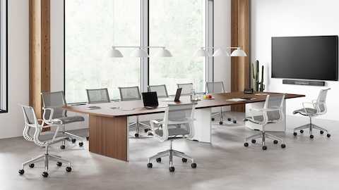An office setting with a Headway conference table with a cabinet base surrounded by gray and white Setu office chairs.