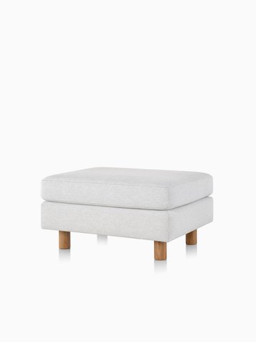 Un ottoman Lispenard grigio chiara con imbottiture in tessuto e gambe in legno chiaro, vista frontale.