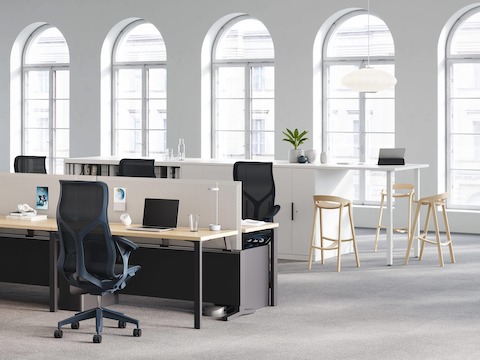 An open plan office with a Canvas Dock workstation acting as the power and data source for a round Logic Reach System Start. Four high-back Cosm office chairs are positioned at the workstation.