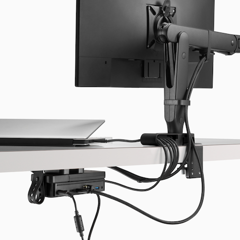 Back view of a monitor screen with power and data cables routed from the connected monitor arm and through an Ondo Connectivity Module and Loop Micro under a desk.