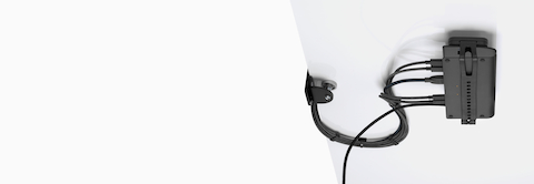 Loop Micro Mount attached under a desk cradling a thin client or power docking station with attached cables that are routed tidily to the edge and above the desk.