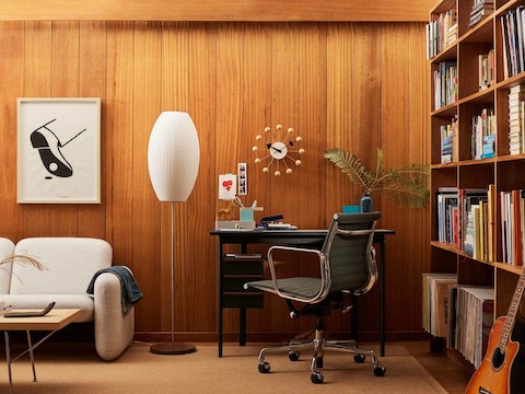 Mode desk in black with sandstone top in a wooden paneled library room with cigar lamp and cream Wilkes sofa.