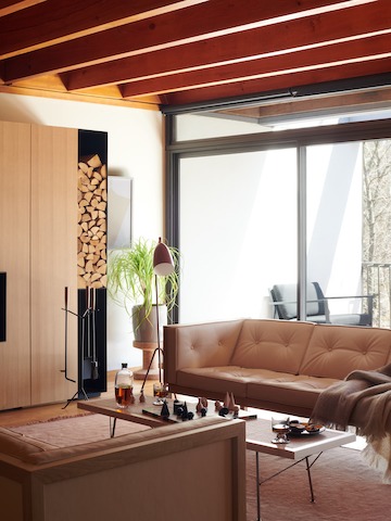 A living space featuring the Nelson Cube Sofa, Nelson Cane Bench, a floor lamp, linen rug, chess set, and fireplace tools.