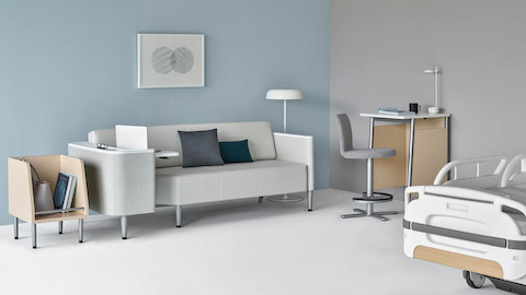 Patient room featuring the Nemschoff  Palisade Flop Sofa in a gray fabric, next to a Nemschoff Palisade Tote, Nemschoff Palisade Daystand, and patient bed.