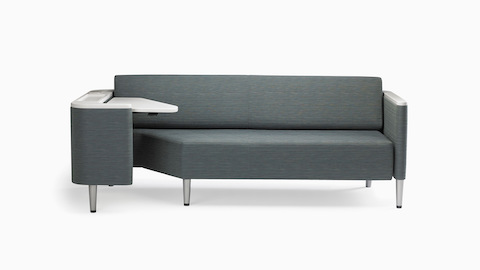 A Nemschoff Palisade Flop sofa in dark gray textile with white solid surface arms caps and white adjustable table with Durawrap top.