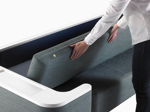 A person positioning the back of a Nemschoff Palisade Flop Sofa into a sleep surface.