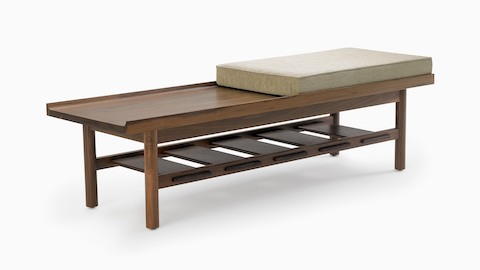 A Tamarack Table and Bench in walnut with a light-colored cushion.