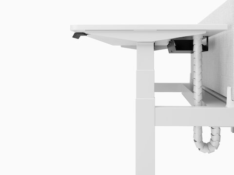 A close-up profile view of a white Nevi Link desk and gray screen showing the T-shaped leg and cable tray under the work surface.