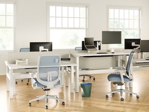 Nevi Link Sit-Stand back-to-back desk configurations in white with gray-colored fabric screens, Lima Monitor Arms and screens, Oripura Laptop Stand, and Verus Chairs.