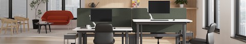 A four-desk configuration of Nevi Sit-to-Stand Desks with Asari Chairs. To the left, a lounge setting with a Womb Settee and Cover Lounge Chairs.