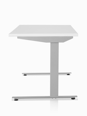 A side view of a Nevi standing desk with a white surface and silver legs.