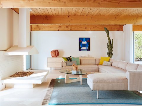 A Noguchi occasional table with a white ash base complements a sectional in a residential setting. 