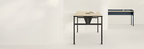 Two OE1 Communal Tables with light brown surfaces and black and blue finishes, viewed from side and front angles.