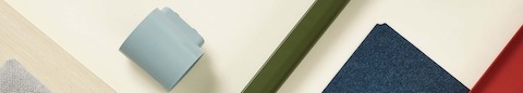 A selection of OE1 Workspace Collection materials, including light brown laminate surface, grey marker cup, green leg, blue fabric and red frame.
