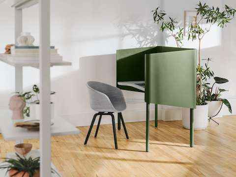 A grey Hay About A Chair at a green OE1 Nook, with a grey OE1 Agile Wall with full shelves in the foreground.
