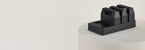 Three black OE1 Power Pack batteries docked on a black OE1 Power Tray, viewed from an angle.