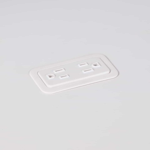 A close-up view of Logic Mini with two power outlets integrated into the top of a white laminate work surface.