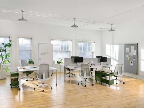 Four grey OE1 Rectangular Tables joined together to form a bench, with a grey OE1 Project Table, green OE1 Storage Trolleys and green Lino Chairs in the foreground and an OE1 Wall Rail and Board in the background.