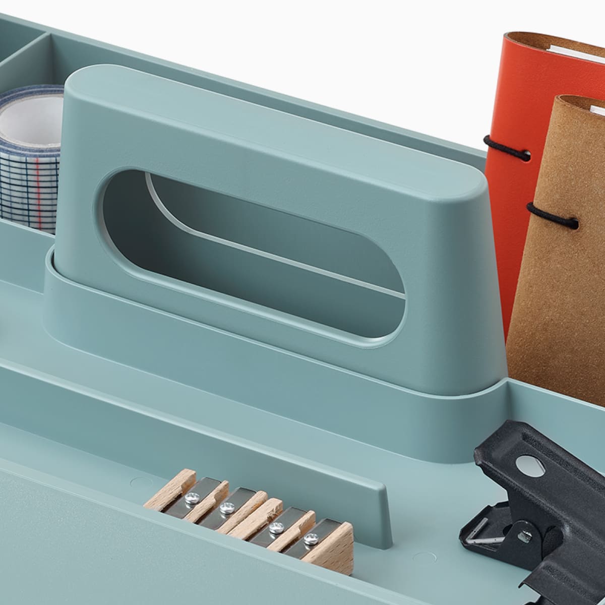 Caja para útiles de trabajo OE1 azul claro con lápices, libretas y otros artículos personales, vista desde un ángulo.