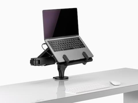 An open laptop held by a black Ollin Laptop Mount connected to an Ollin Monitor Arm.