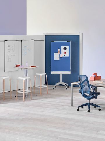 An Overlay space with markerboards and blue tackable fabric divider surrounding a table and stools.