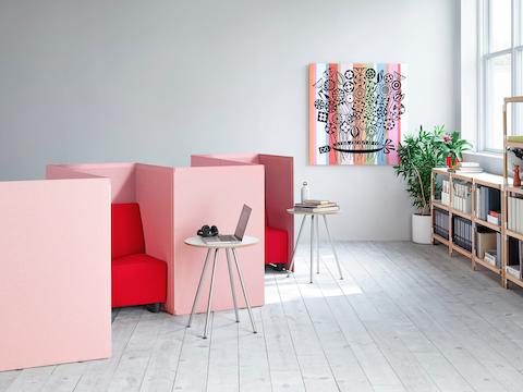 Light red fabric Pari freestanding privacy screens connected to each other in a zigzag pattern with a red Swoop chair placed into each nook.