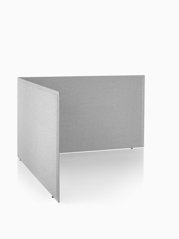 Viewed at an angle, two gray fabric Pari freestanding privacy screens connected in a L-shape configuration with a settee, end table, and lamp in it.