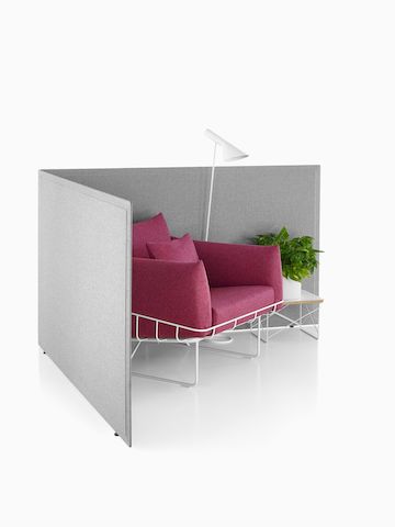 Viewed at an angle, two gray fabric Pari freestanding privacy screens connected in a L-shape configuration.