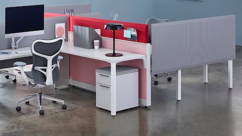 Las pantallas Pari conectadas a la superficie y unidas en el marco en tonos de gris, rosa y rojo crean límites en un área de trabajo abierta.