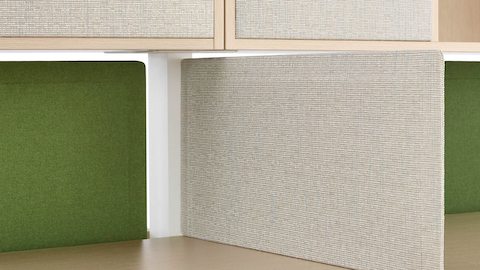 Una pantalla Pari de color gris claro brinda privacidad al adherirse a la costura entre las superficies de trabajo adyacentes.