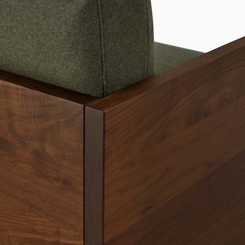 A detail view of the Pawson Drift Sofa Groups back corned with solid wood walnut and a green textile.