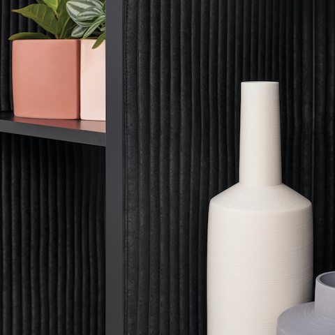 A close-up of the wooden framed black open shelf of Port Storage System showcasing the details of a decorated cabinet.