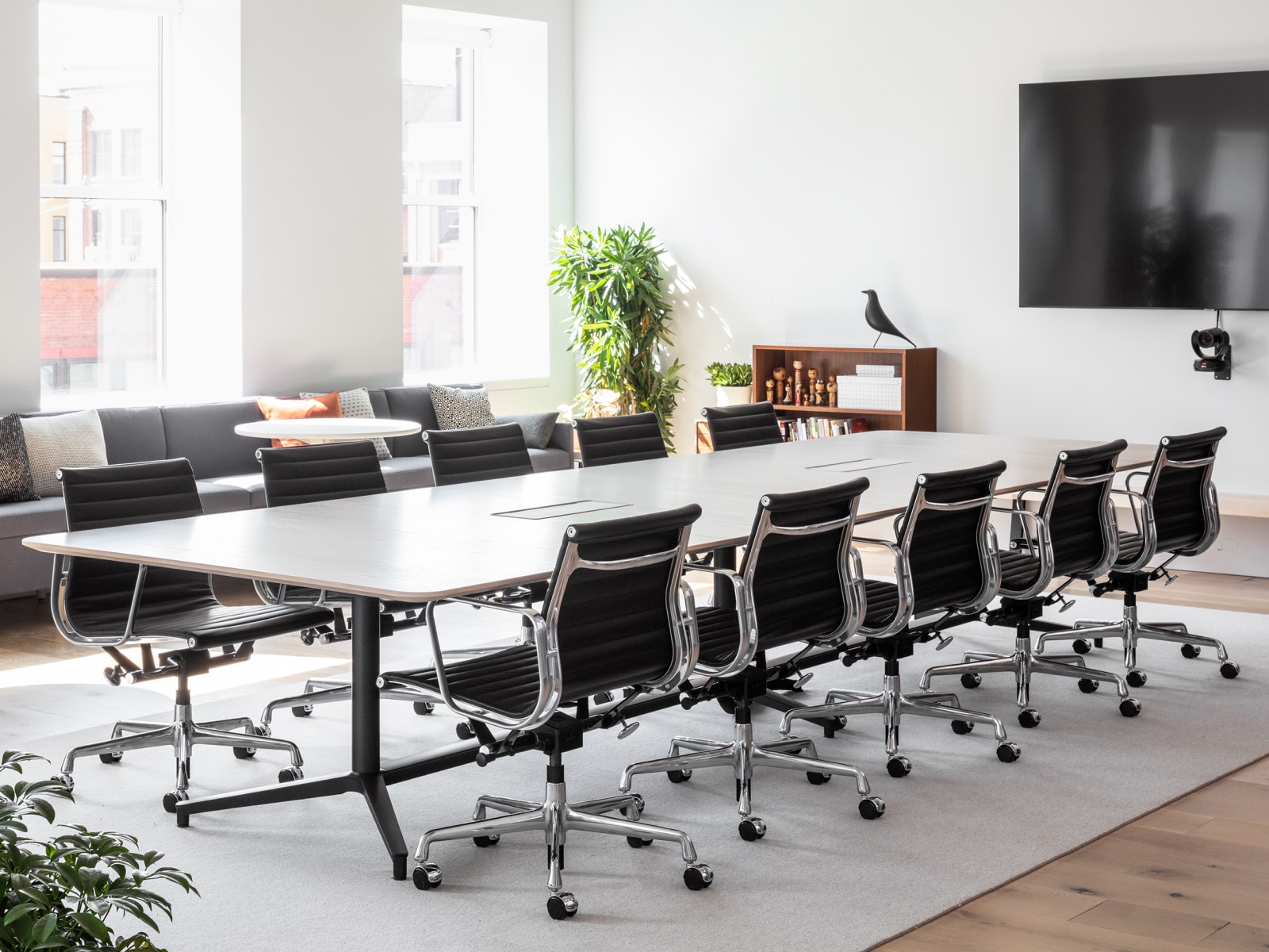 A large, well-lit conference room with a Headway Table and ten black Eames Aluminum Group Chairs.