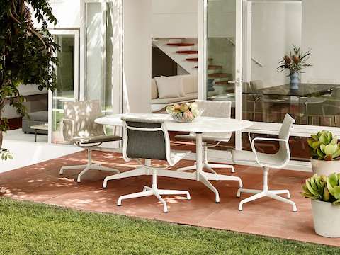 Four Eames Aluminum Group Side Chairs-Outdoor surround an Eames Table-Outdoor in a patio setting.