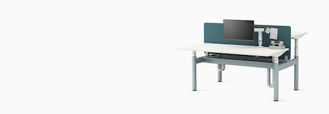 Back to back Ratio height-adjustable desks positioned at seating and standing heights, with back to back shared privacy screen on a white sweep.