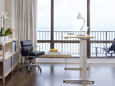 An office with a Renew Sit-to-Stand Table, an Eames Soft Pad Management Chair, a Nelson Platform Bench, and a Magis Steelwood Shelf.