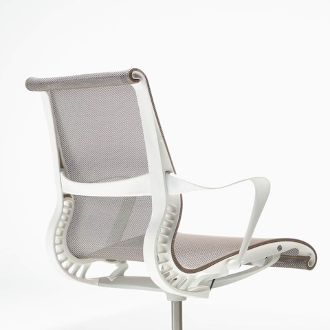A rear-angle view of a Setu chair with fixed arms, a studio white frame, silver alloy base, and cocoa brown suspension.