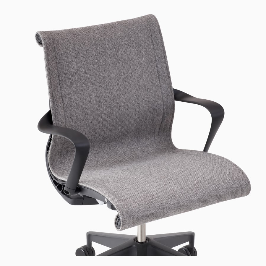 A close-up view of an upholstered Setu chair with arms in gray.