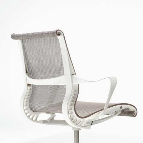 Rear-angle view of a Setu chair with fixed arms, a studio white frame, silver alloy base, and cocoa brown suspension.