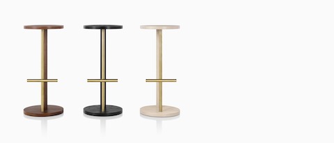 Three Spot Stools of different heights, featuring a circular seat and base connected by two parallel legs of wood and metal. 
