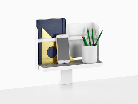 Una mensola allegata Ubi con uno sfondo supporta un libro, uno smartphone e una tazza per le matite.