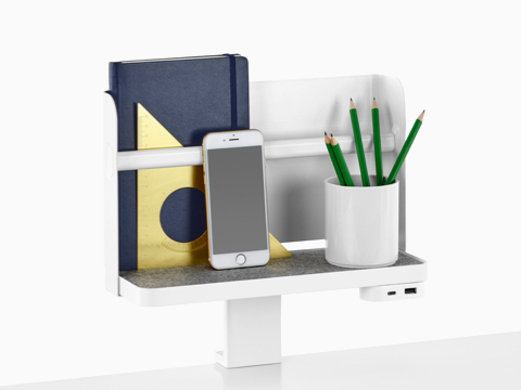 A Ubi Attached Shelf with a backdrop supports a book, smartphone, pencil cup, and USB power module.