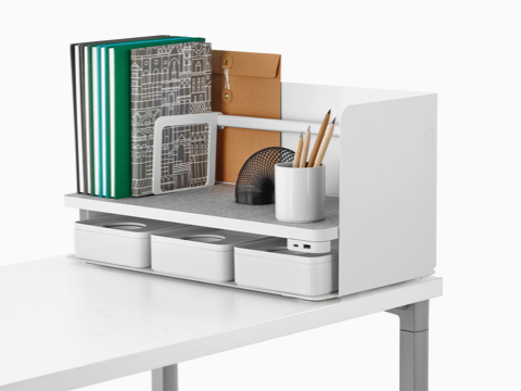 Books and a pencil cup sit on the shelf of a Ubi Organizer, which also includes three storage boxes and a USB power module.