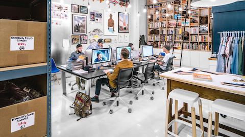 People work at their computer desks in a collaborative environment, while seated in Setu chairs. 